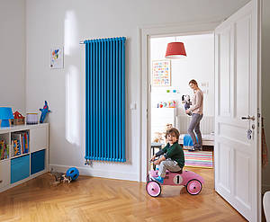 Blau auf Weiß: Der Mehrsäuler Zehnder Charleston zeigt sich im beeindruckenden, raumhohen Sonderformat in der Farbe „Horizon Blue“ als farbenfroher Wärmespender im Kinderzimmer